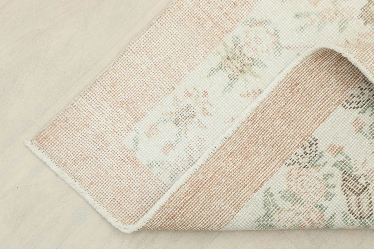 Corner of the vintage rug folded back to show the underside and pile thickness