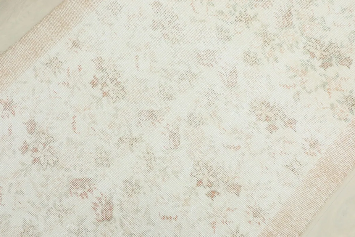 Overhead close-up showing the faded floral motifs and gentle color variations across the rug's field