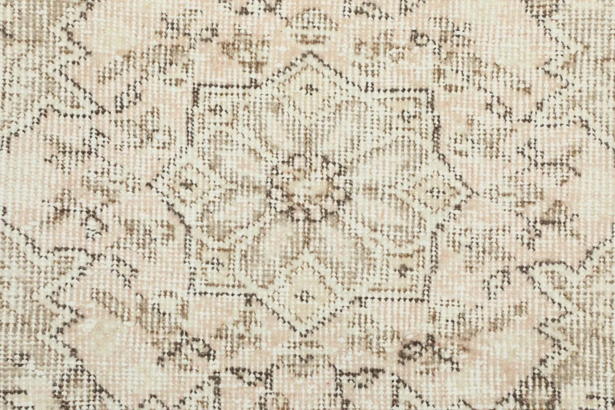 Extreme close-up of the wool pile, showing the texture and muted colors of the geometric patterns.