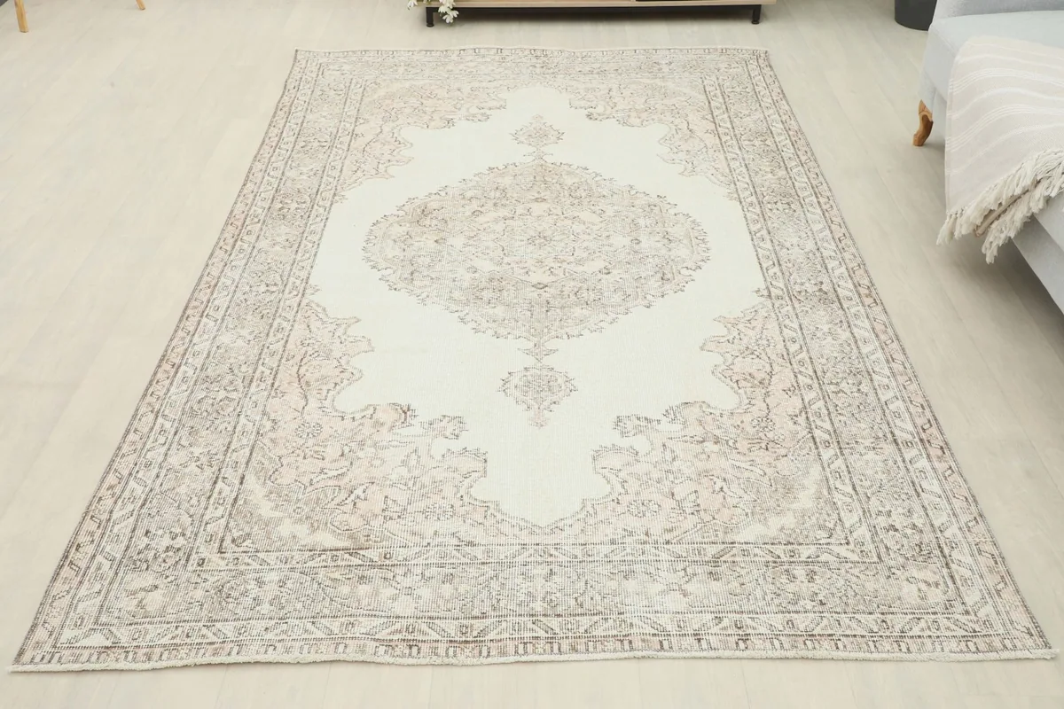 Full overhead view of the vintage ivory and beige area rug, showcasing its complete design in a room setting.