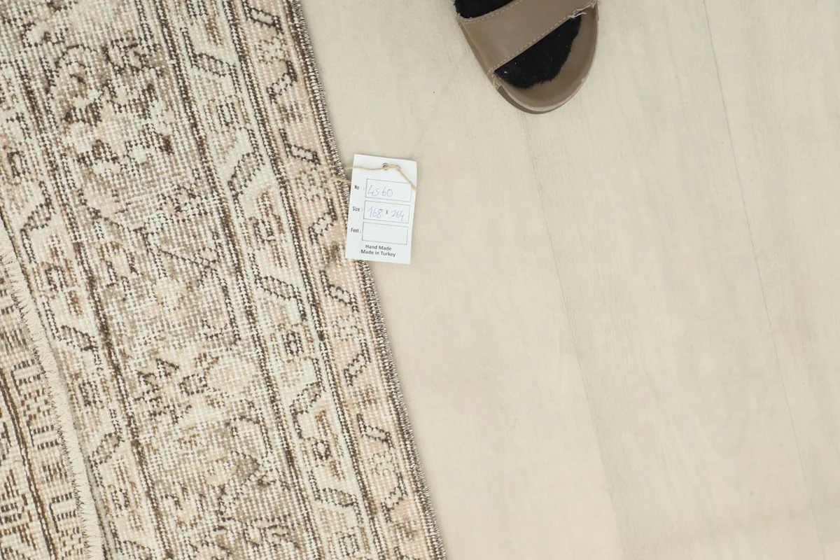 Overhead view showing the rug's edge next to a foot, illustrating scale and the low pile texture.
