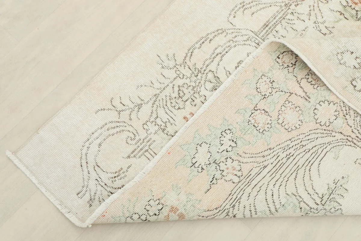 Corner of the rug folded back, showing the thickness and construction of the hand-knotted piece.
