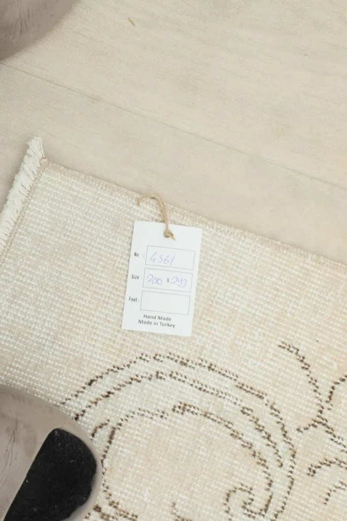 Product tag showing rug dimensions and origin, attached to the corner of the vintage rug.