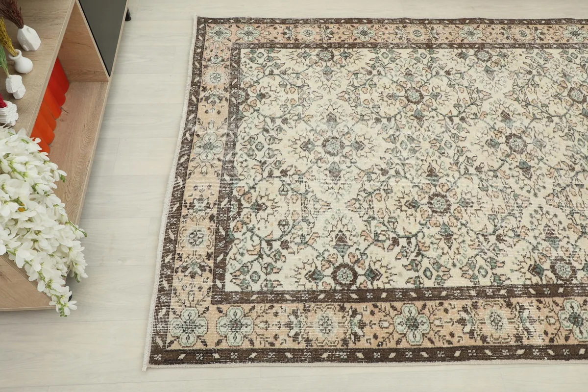 Overhead angle view of the ivory rug's floral pattern and rose border