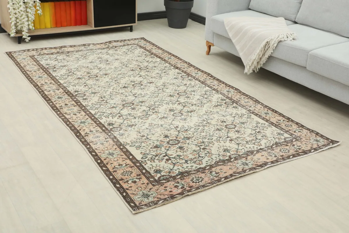 Angle view of the ivory and rose rug in a living room with a gray sofa