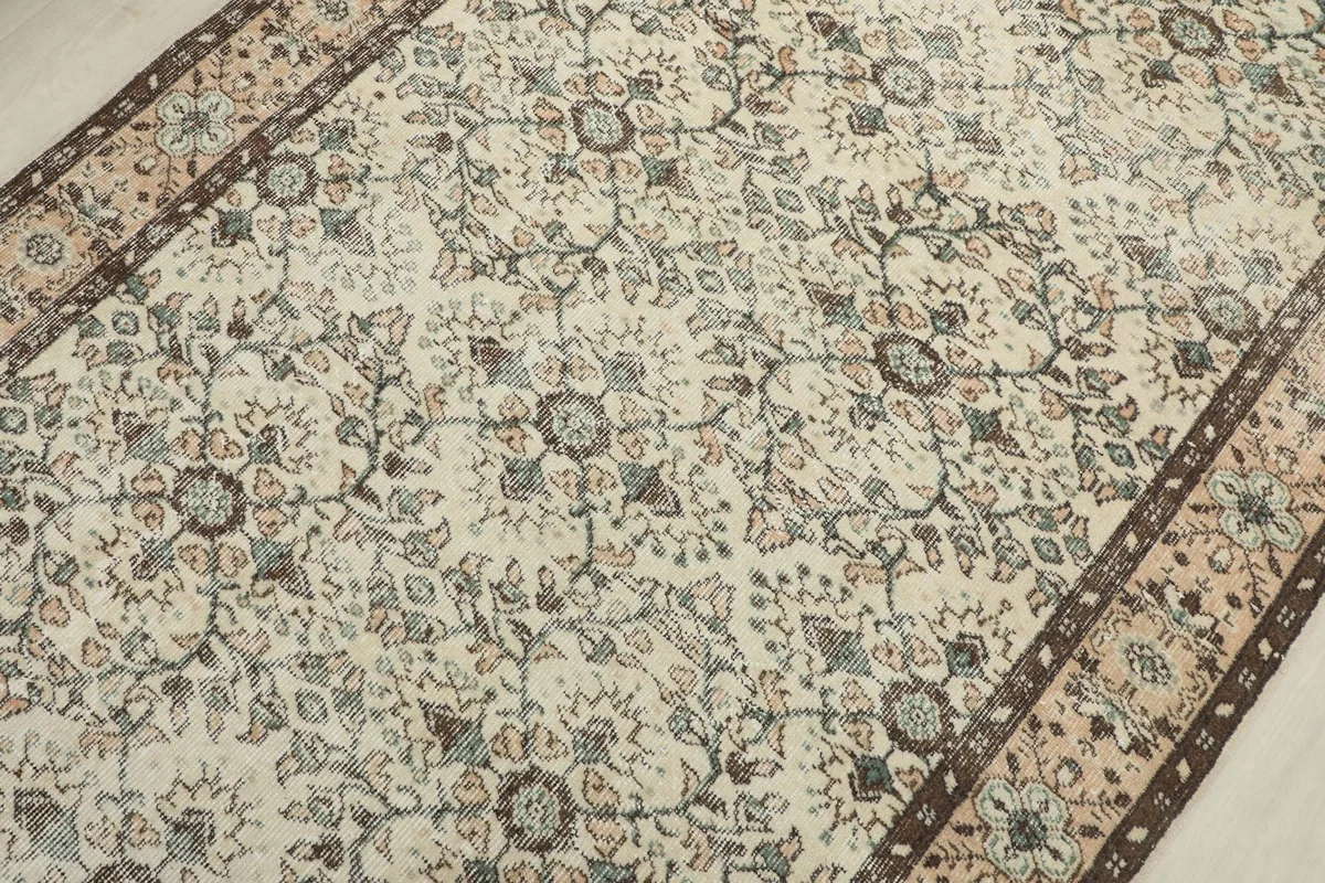 Close-up view of the central ivory field with brown and green floral motifs