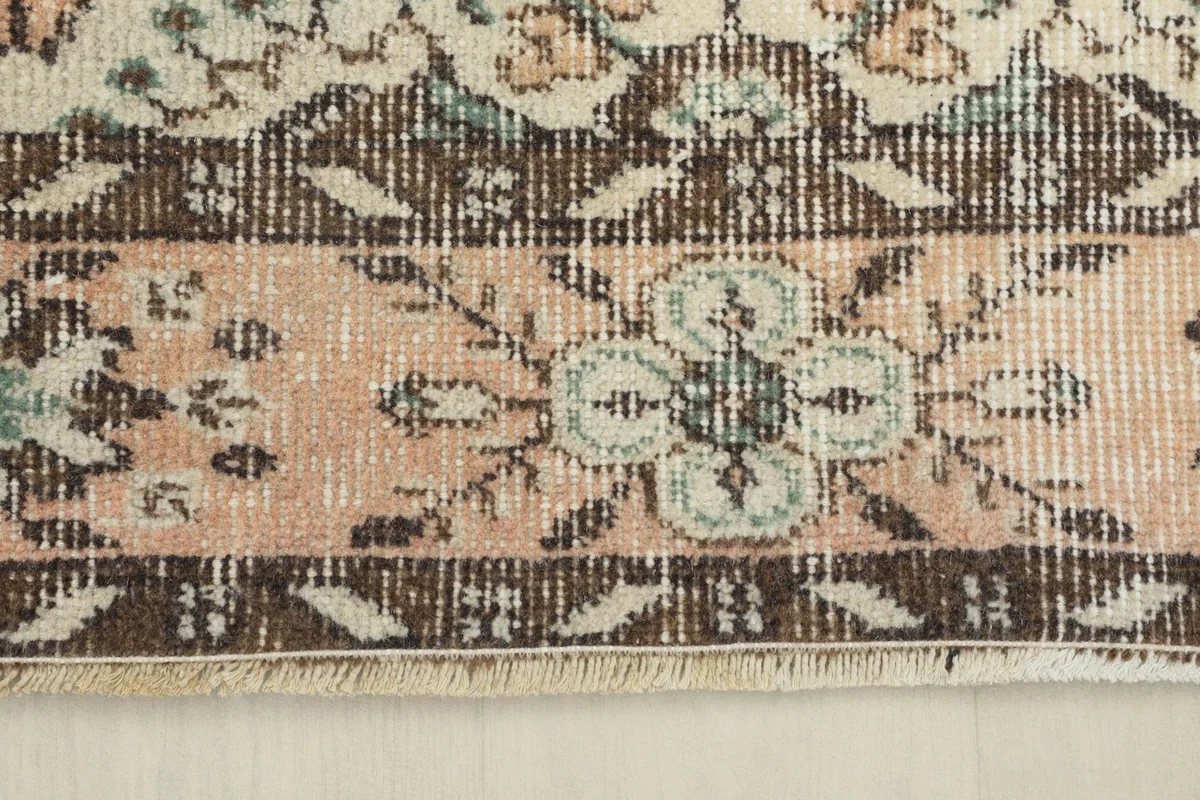 Close-up of the rose-colored main border with floral designs and brown outer border