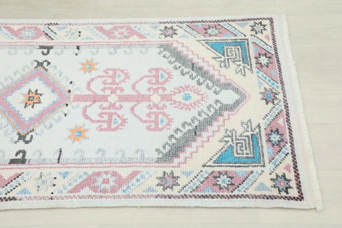 Close-up detail of one end of the runner, highlighting the geometric patterns in rose, blue, and gray.