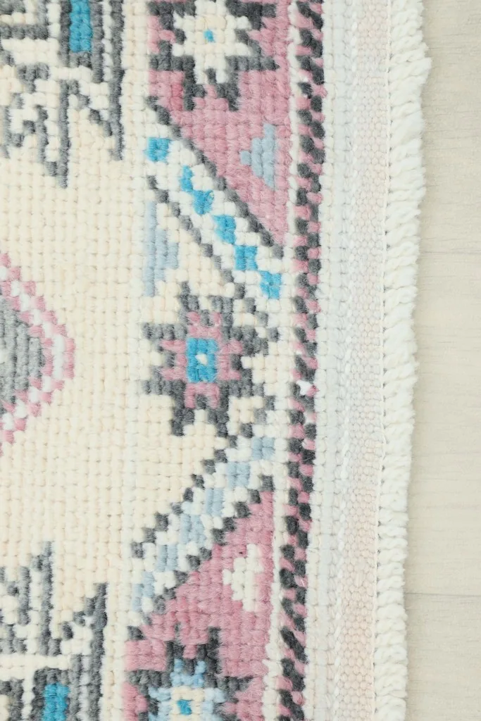 Close-up of the rug's side border and fringe, illustrating the hand-knotted wool pile and cotton foundation.