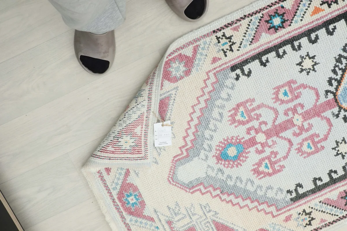 Close-up of the rug's reverse side with a tag, showing the tightly woven cotton foundation and wool knots.