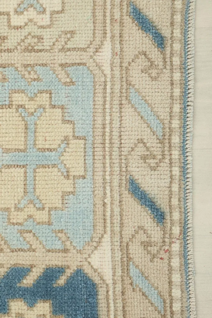 Side view of the rug's edge, illustrating the low pile height and hand-knotted texture.