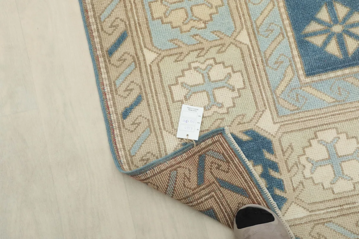 Detail of the rug's reverse side and foundation, with a tag showing product information.