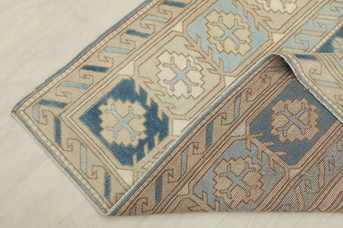 Rug corner folded over, revealing the cotton foundation and the reverse side of the weave.