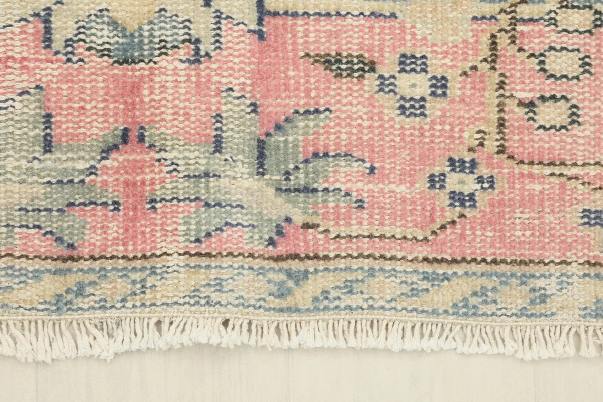 Close-up of the rose border pattern and delicate fringe of the wool rug