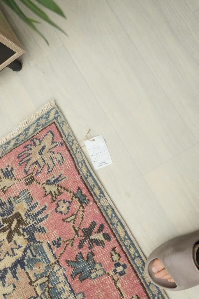Overhead view showing a small section of the rug, a tag, and a foot for scale