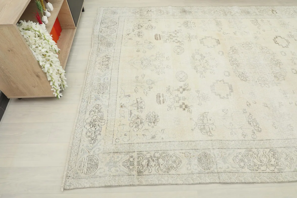 Corner view of the vintage rug, showcasing the subtle border design and overall light color palette.