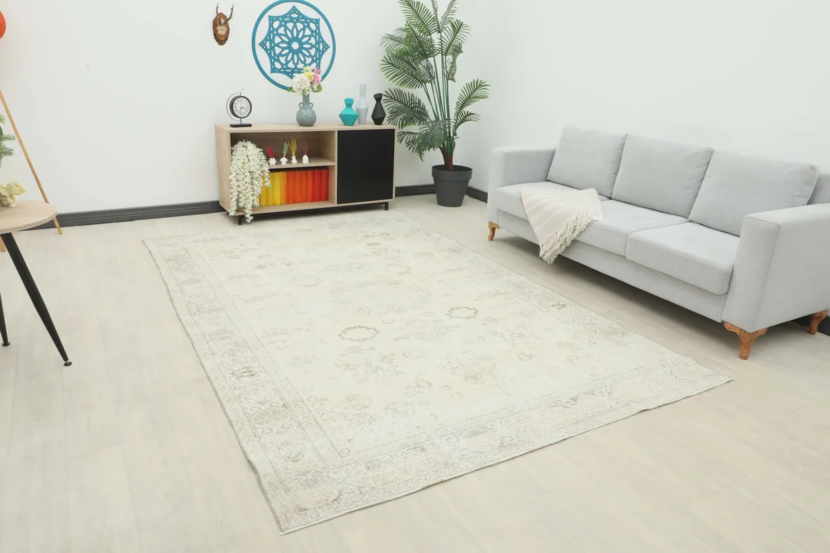 Vintage ivory and beige rug placed in a living room setup with a gray sofa and light wood flooring.