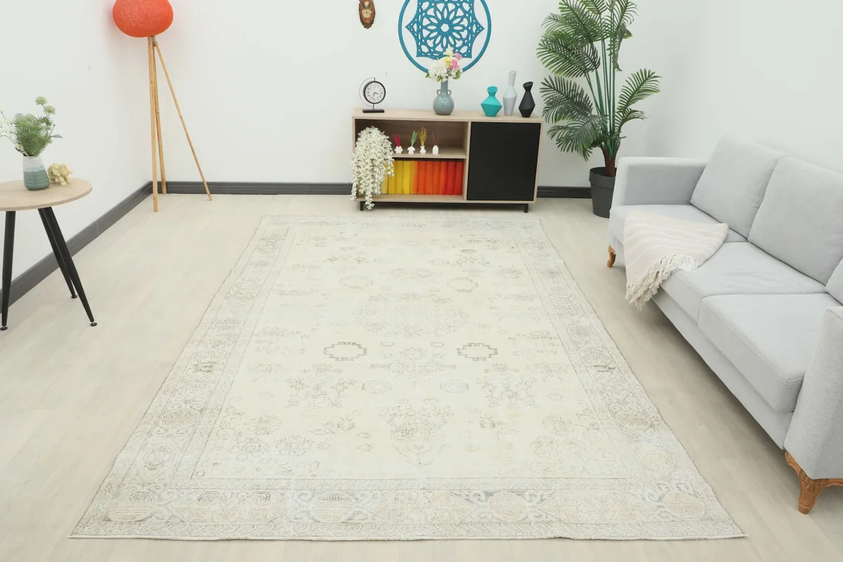 Full room view of the 6'7" x 9'10" ivory and beige vintage rug as a centerpiece in a living area.