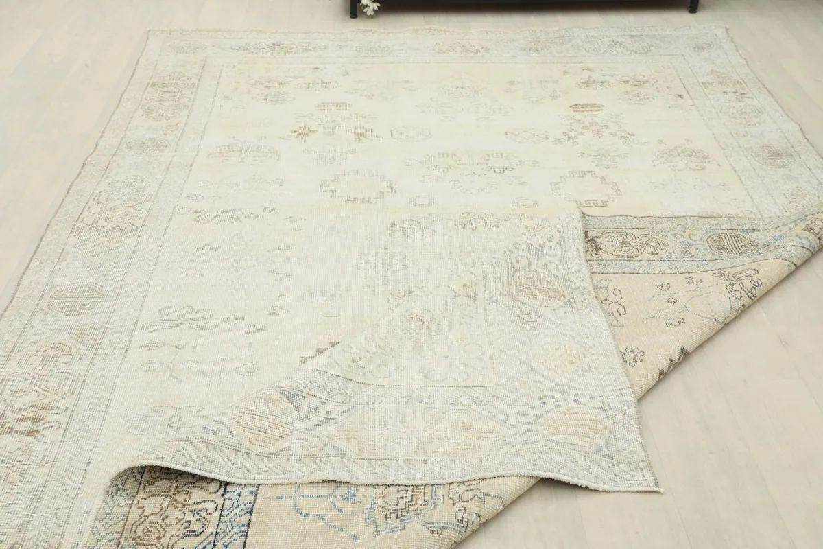 Rug partially folded, revealing the woven back and the soft, flexible nature of the vintage wool.
