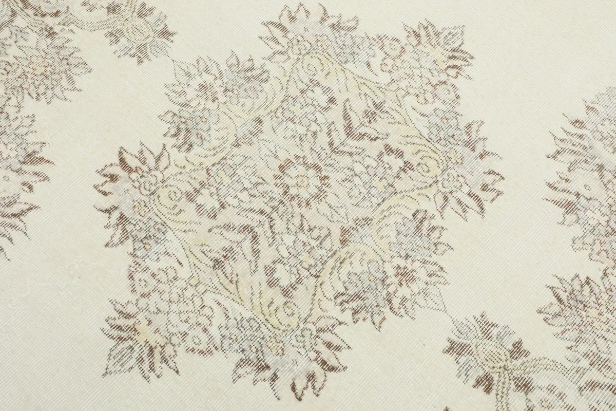 Detailed view of the central medallion-like floral motif on the ivory and gray vintage rug