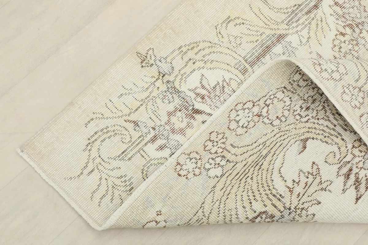 Corner of the rug folded back, showcasing the hand-knotted construction and cotton foundation