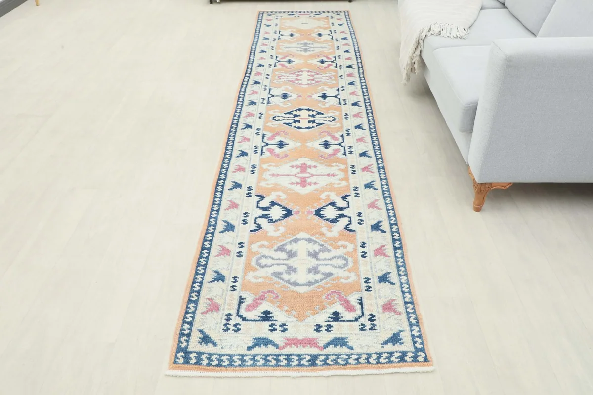 Full overhead view of the runner rug laid out in a room, next to a light gray sofa