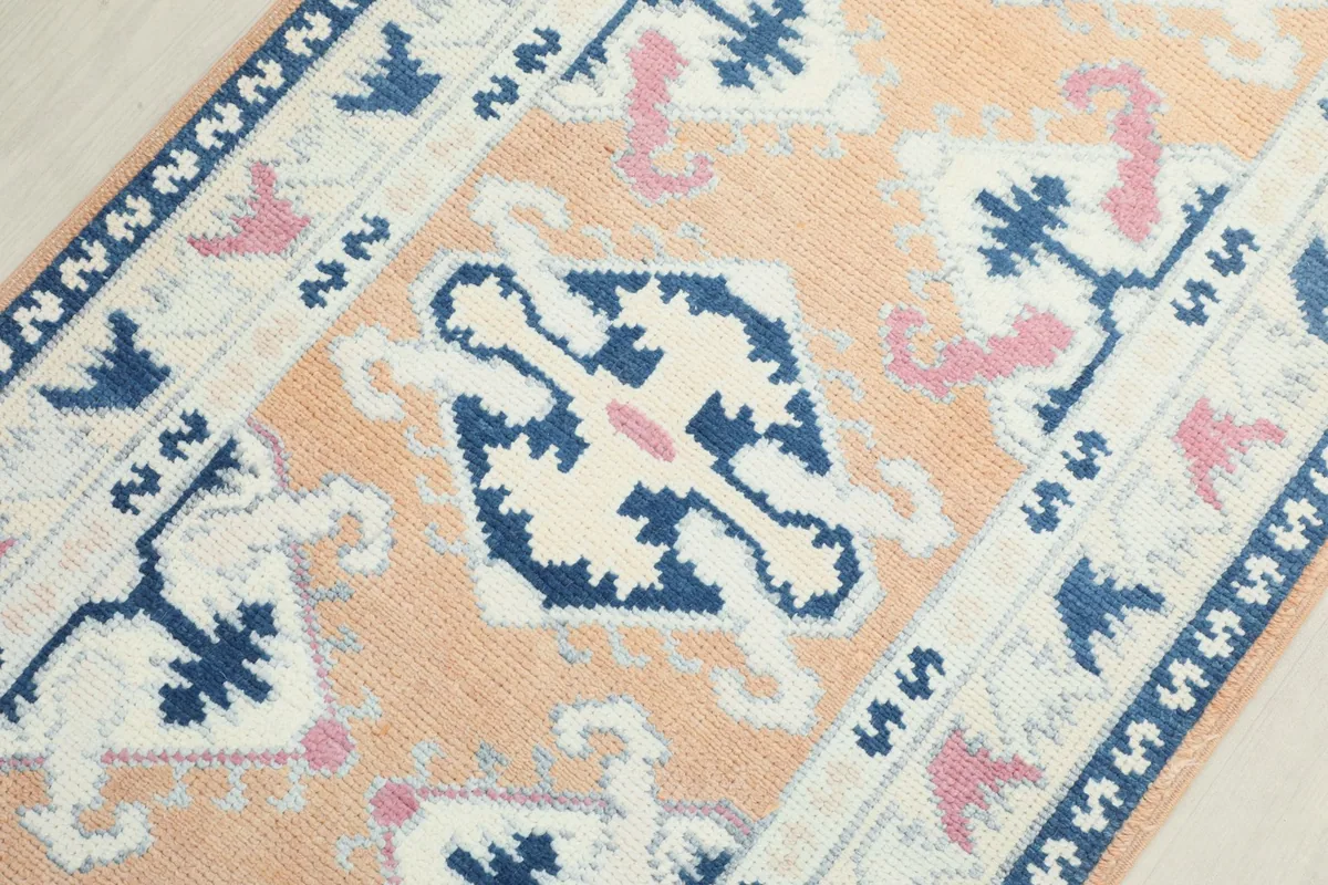 Detailed view of the rug's central motifs, featuring navy and ivory patterns on an orange background