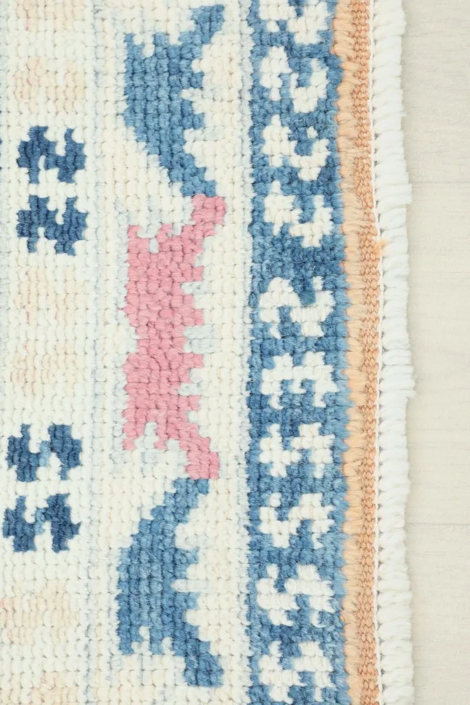 Close-up of the rug's border and fringe, showcasing the hand-knotted texture and colors