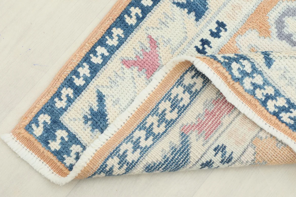 Corner of the rug folded back, revealing the wool pile and cotton foundation