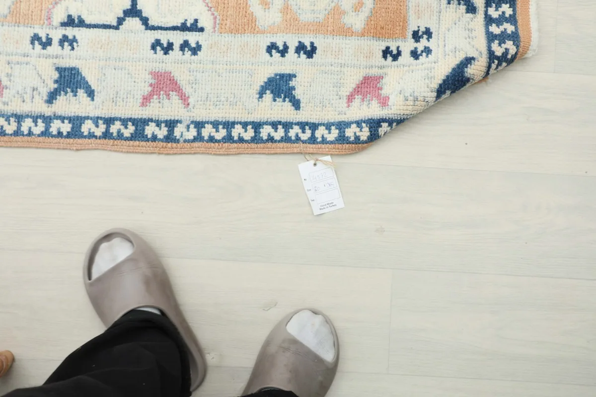 Overhead view of a person's feet near the rug, showing its scale in a room