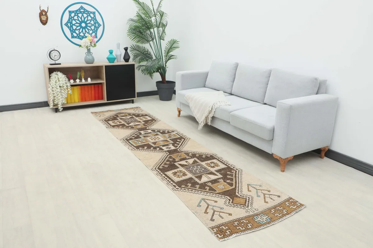 Vintage Anatolian runner rug displayed in a living room setting, showing its length and design next to a sofa.