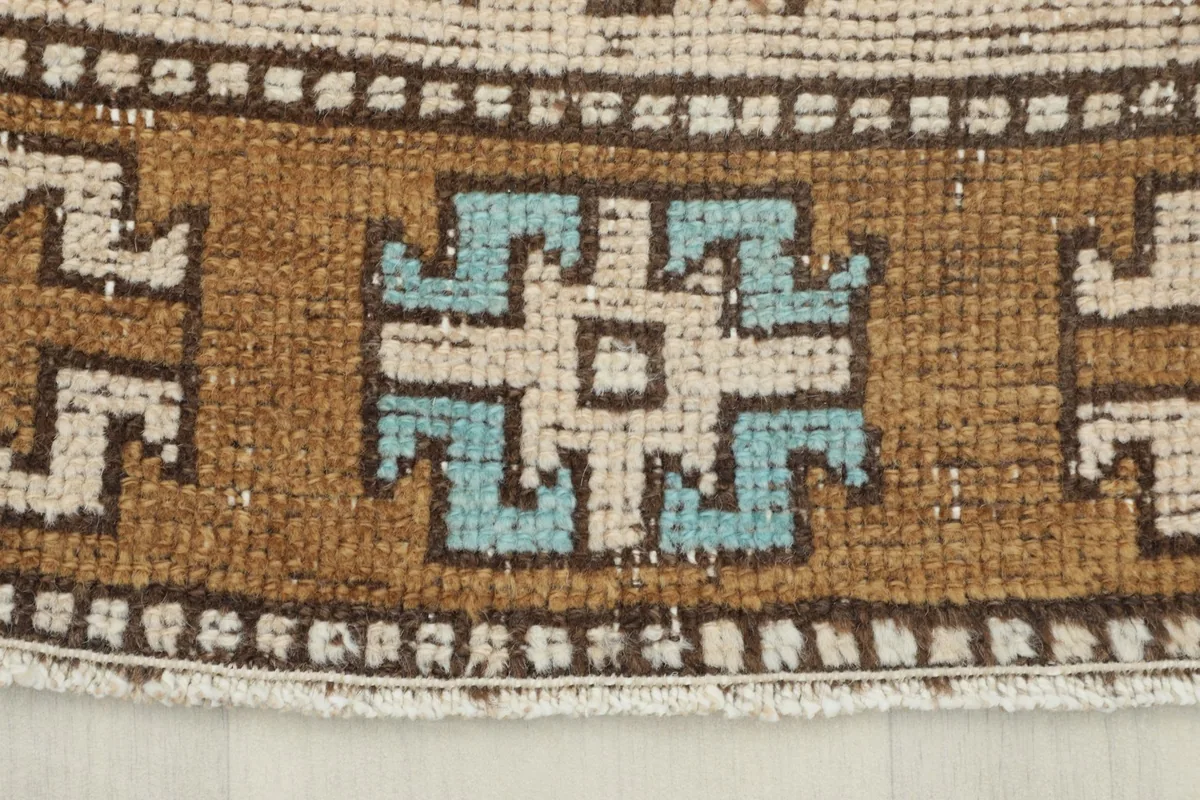 Close-up of the rug's border design, featuring intricate brown and beige patterns with a touch of blue.