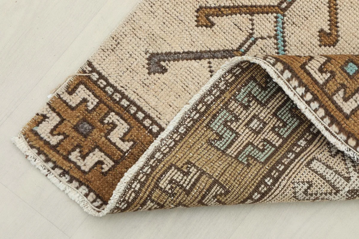 View of the back of the rug where it is folded, revealing the cotton foundation and knotting.