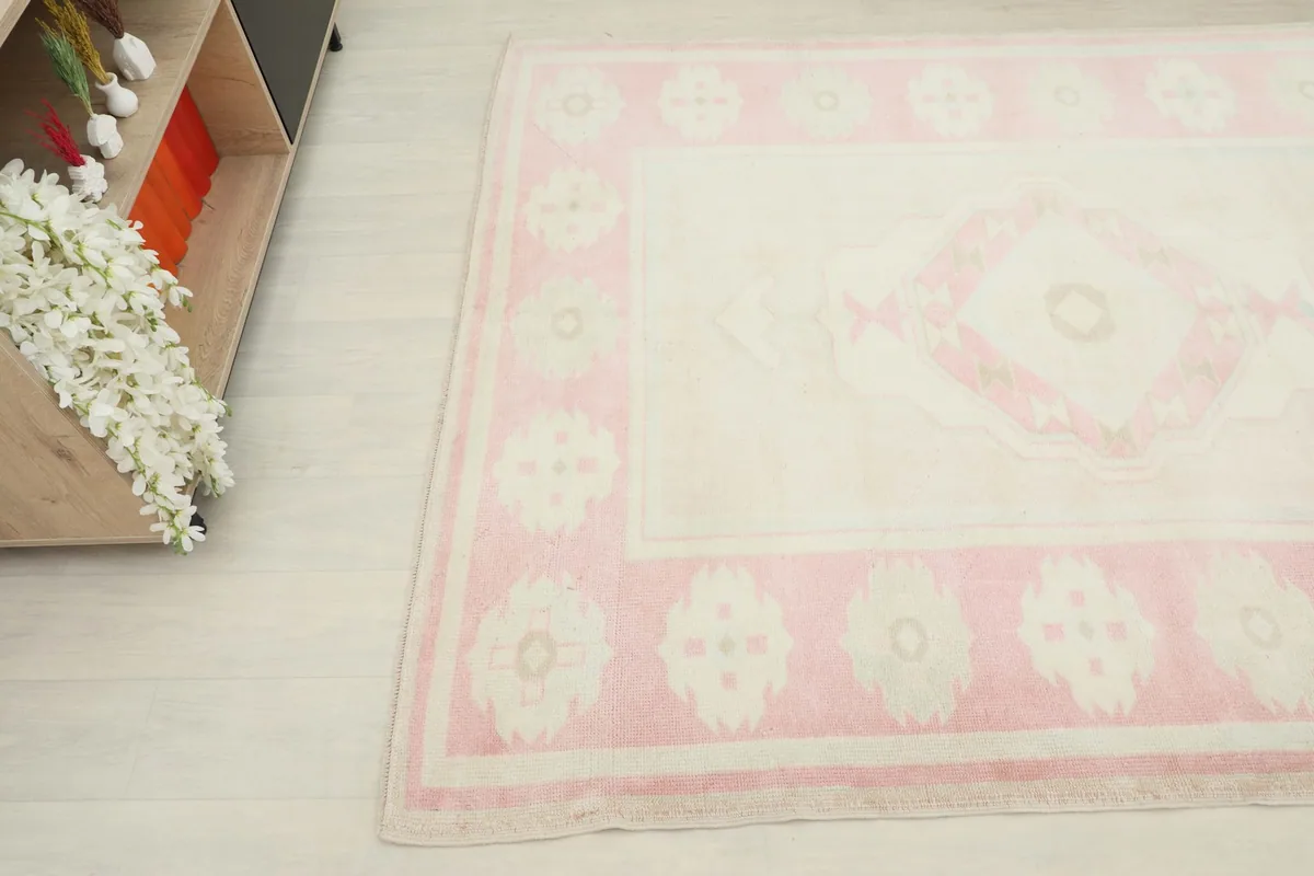 Corner view of the rug, showing the blend of pink, beige, and gray colors in the border design