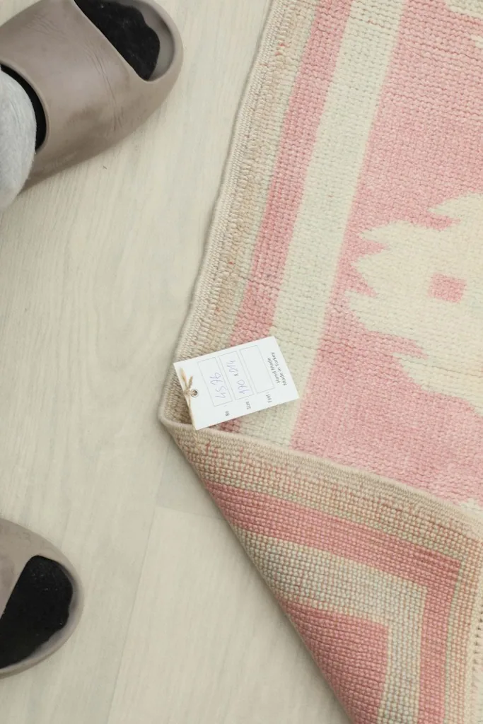 Close-up of the care label attached to the rug's corner, next to a person's feet