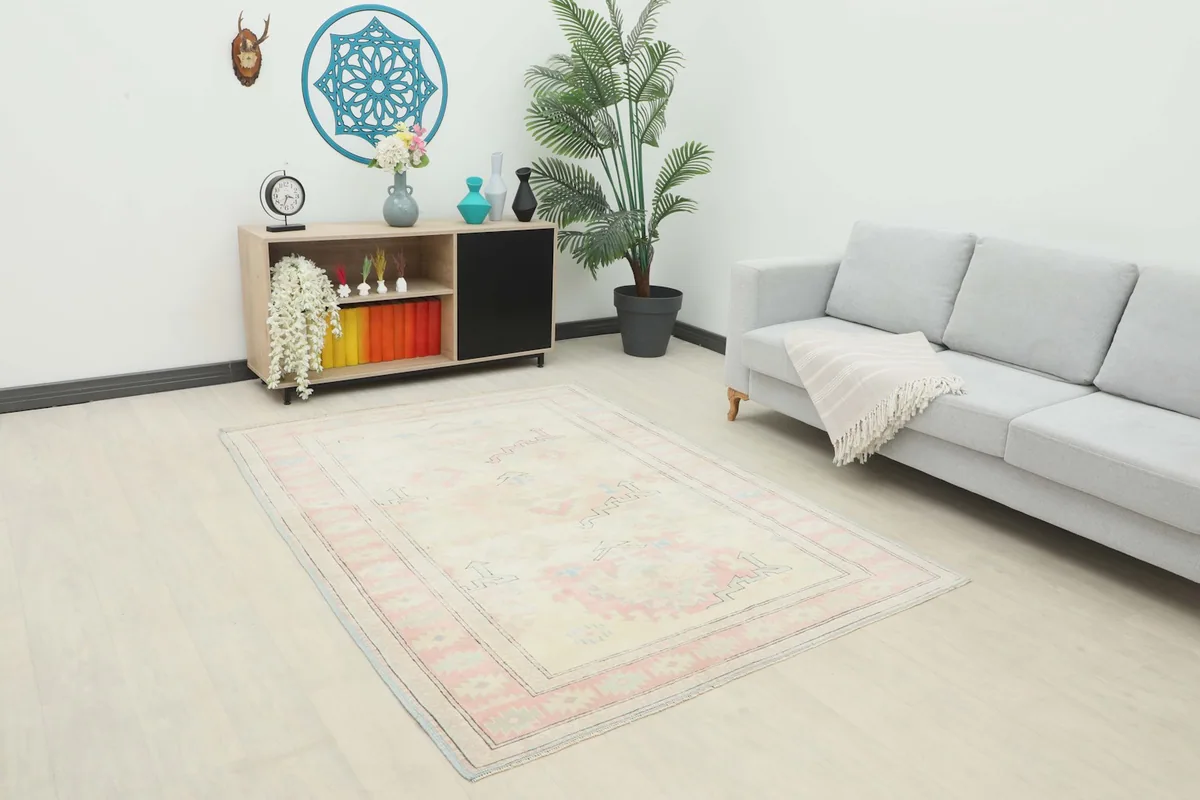 Vintage Anatolian rug in a modern living room setting, showing its scale next to a light gray sofa and wooden shelf.