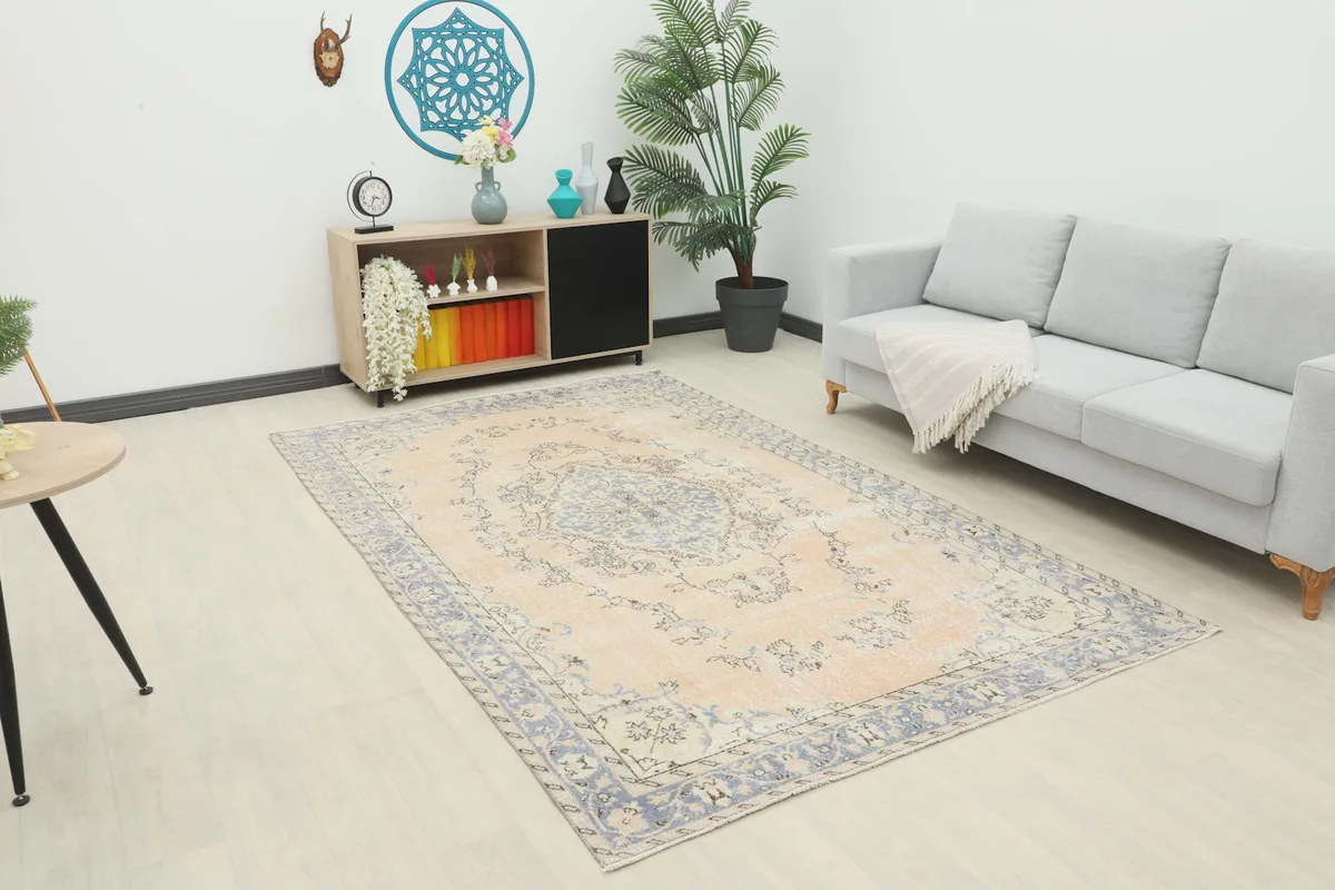 Vintage Anatolian rug displayed in a modern living room setting with a sofa and cabinet.