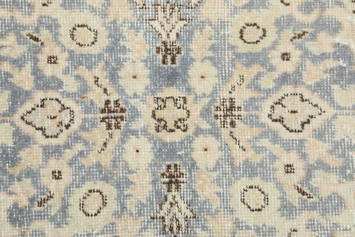 Extreme close-up of the rug's pile, showing the texture and faded blue and beige colors.