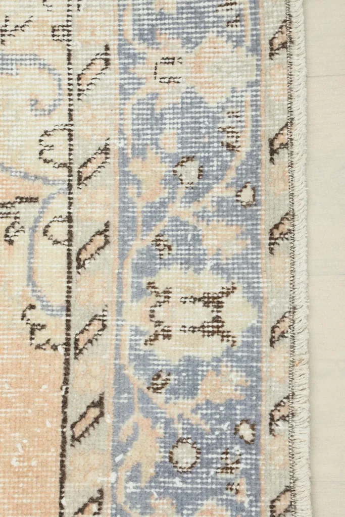 Close-up of the rug's blue border and edge, revealing the hand-knotted craftsmanship.