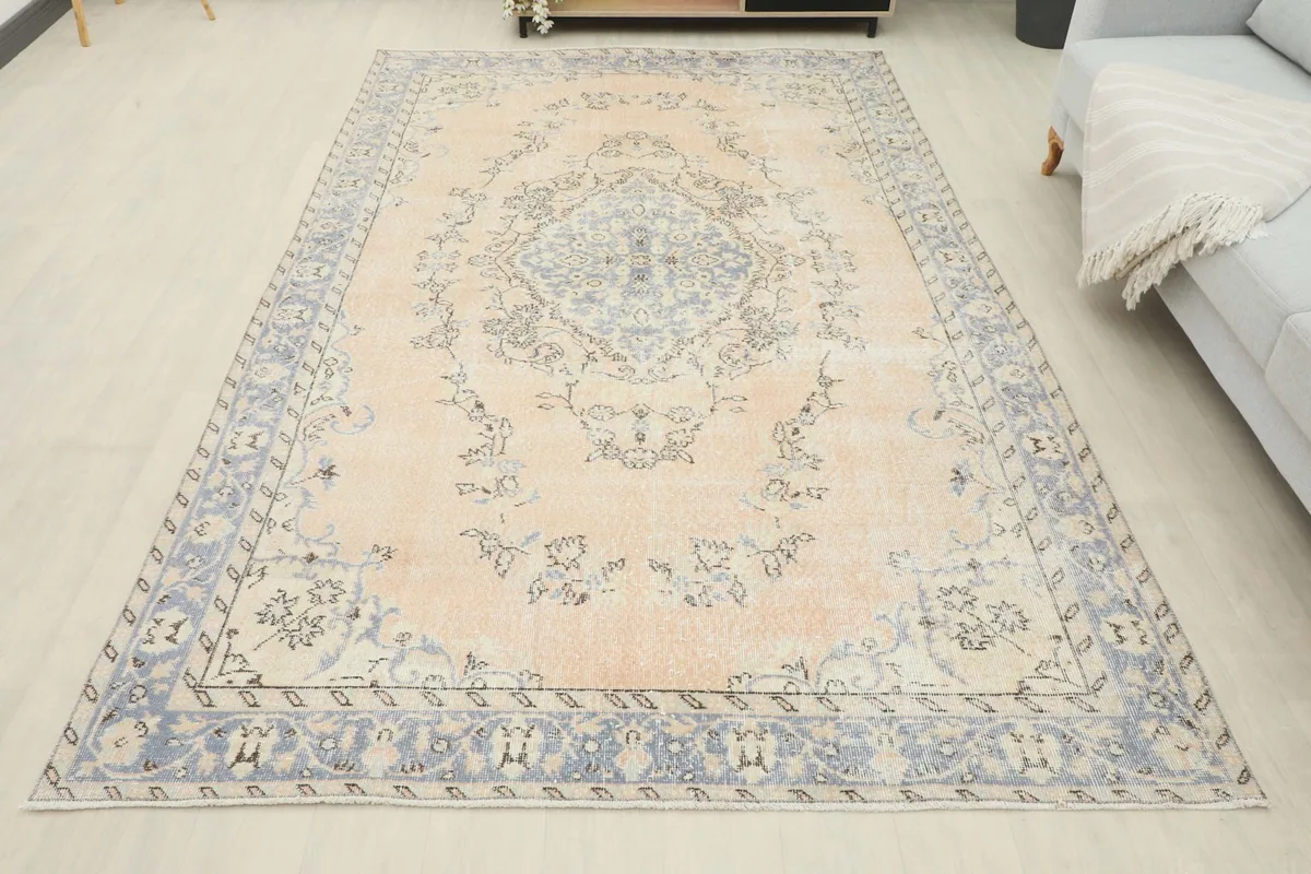 Full overhead view of the beige and blue vintage rug in a room, showcasing its overall design.