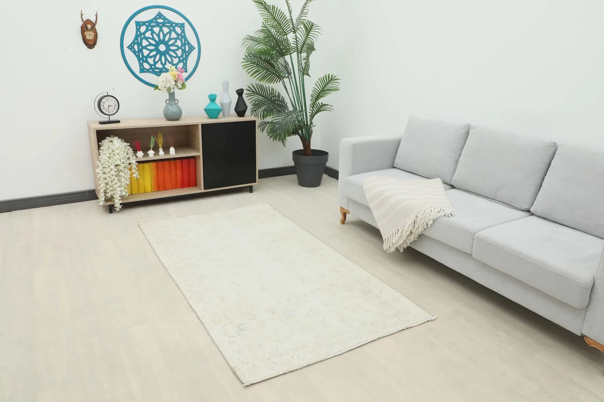 Cream botanical rug placed in a modern living room setting with a gray sofa