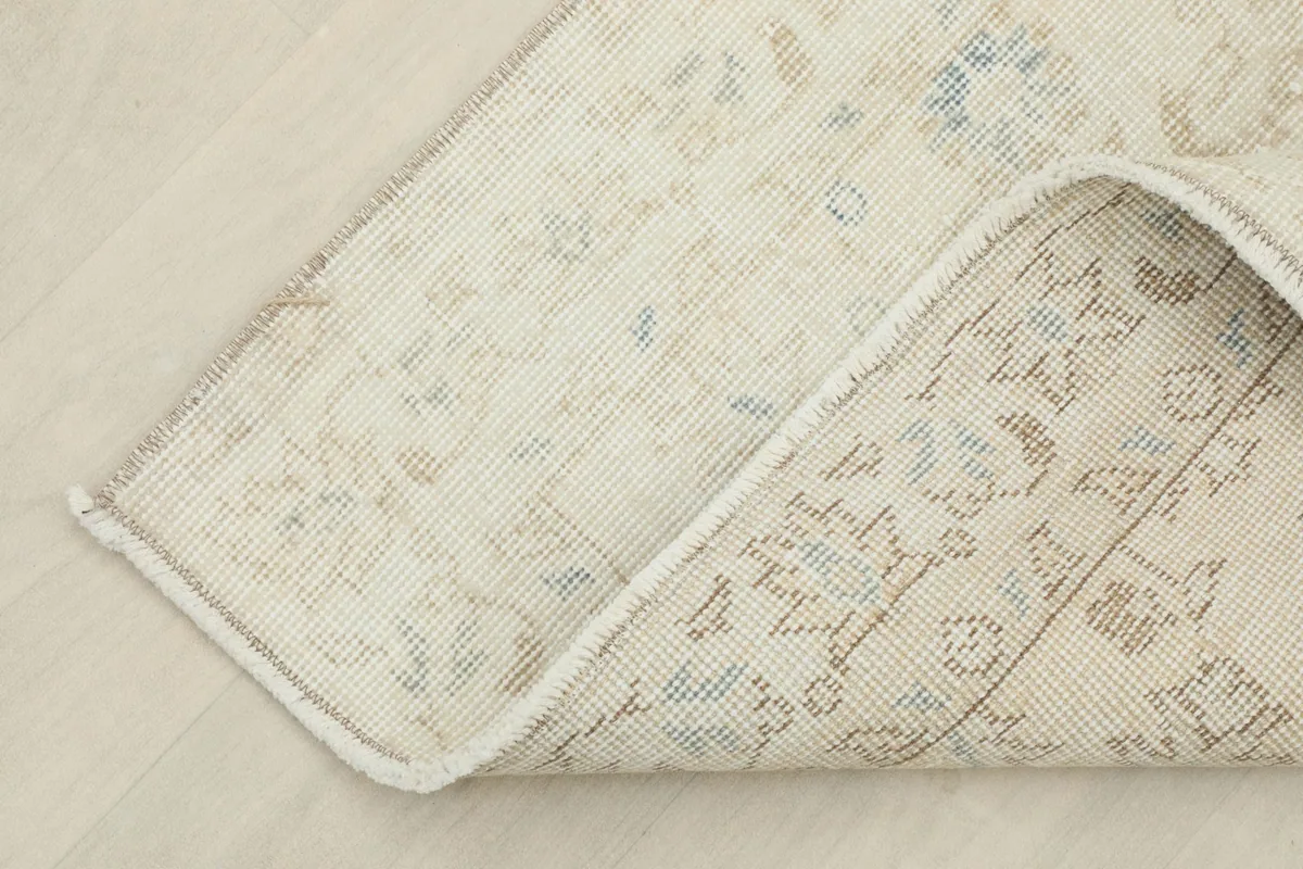 View of the back of the rug folded to show the cotton foundation and knotting