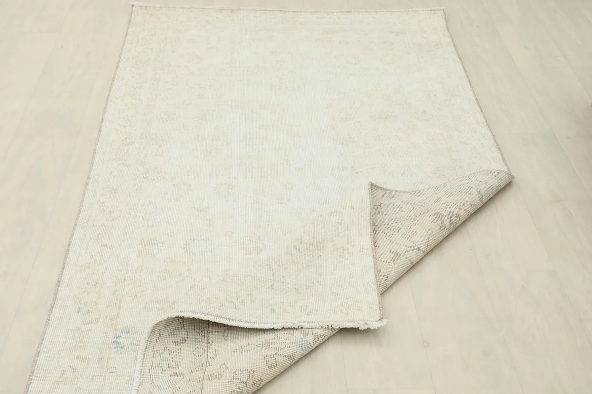 The cream vintage rug partially folded, showing its flexibility and full view