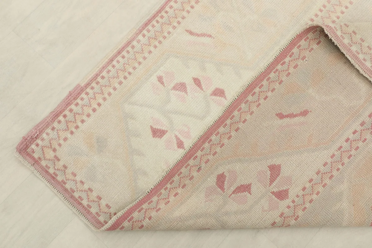 Corner of the rug folded to reveal the thickness and the back of the hand-knotted construction