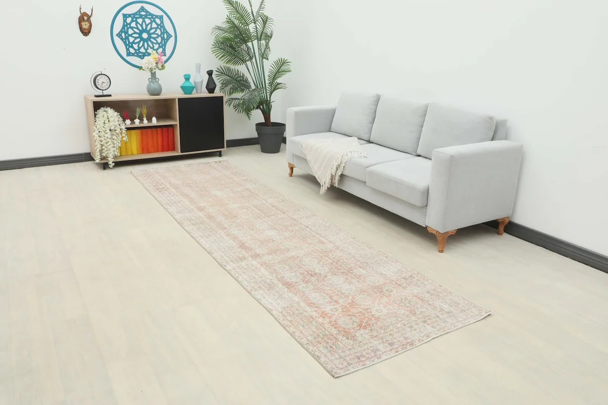 Vintage runner rug in a long hallway, complementing a light gray sofa and wooden cabinet.