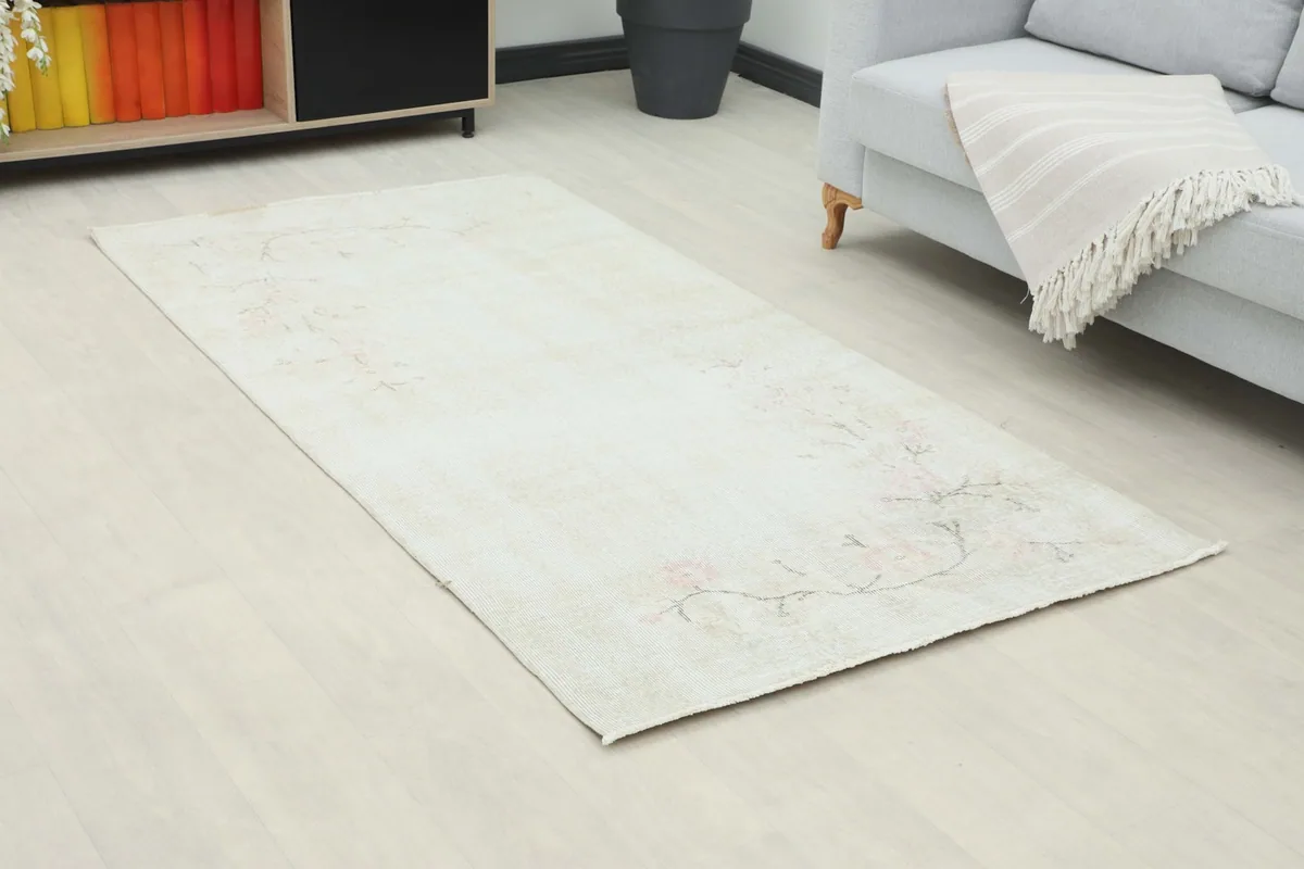 Angle view of the cream and pink vintage rug on a light floor in a room