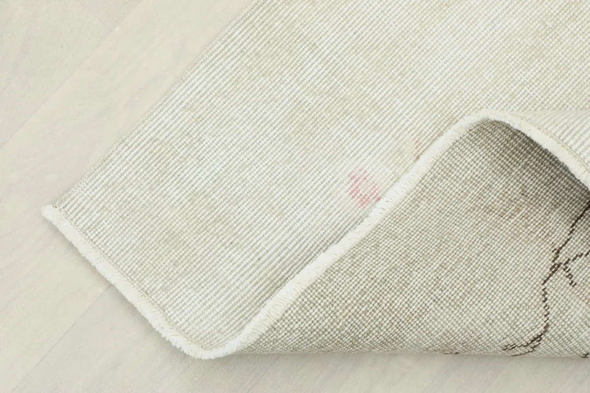 Corner of the rug folded back, revealing the reverse side and foundation