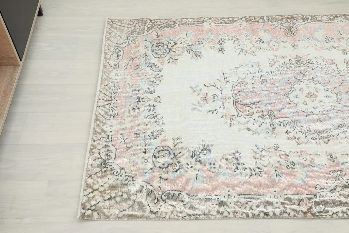 Close-up angle view of the rug's top left corner, detailing the floral motifs and border