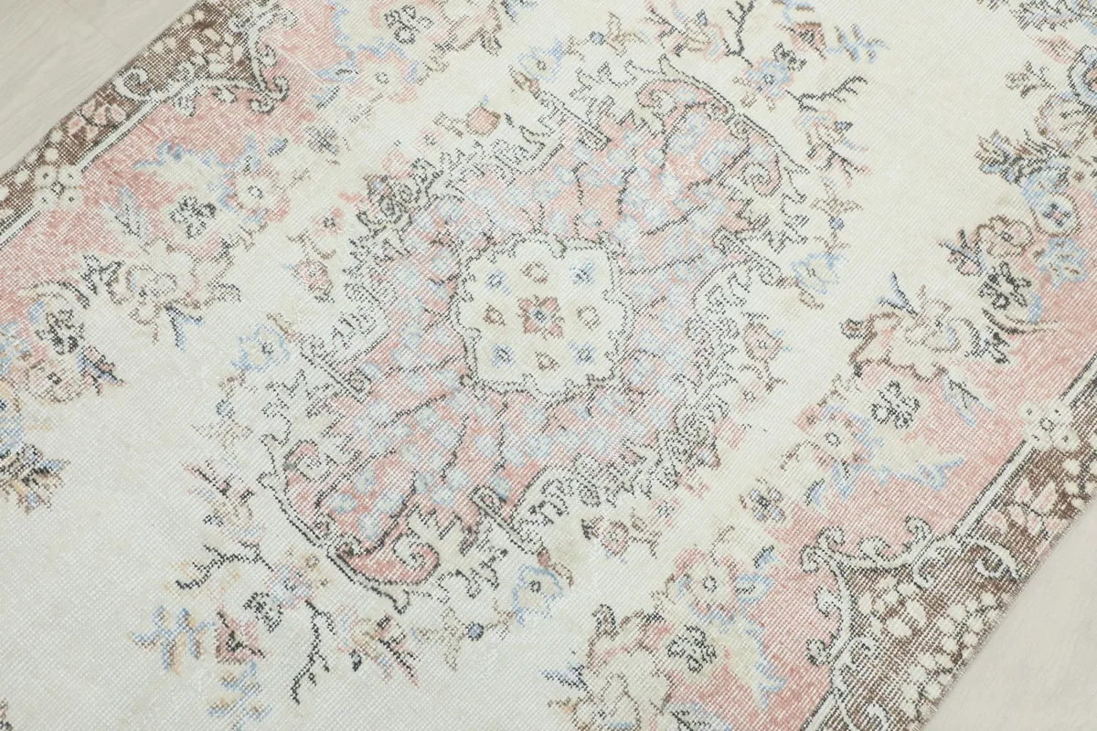 Detailed view of the central floral medallion with rose, ivory, and gray tones