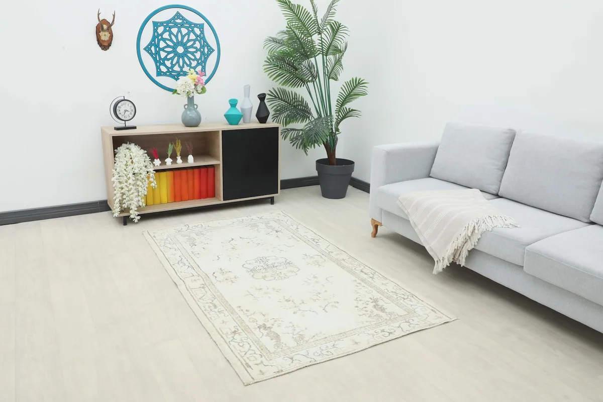 Ivory gray rug placed in a living room setting with a light sofa and wooden cabinet.